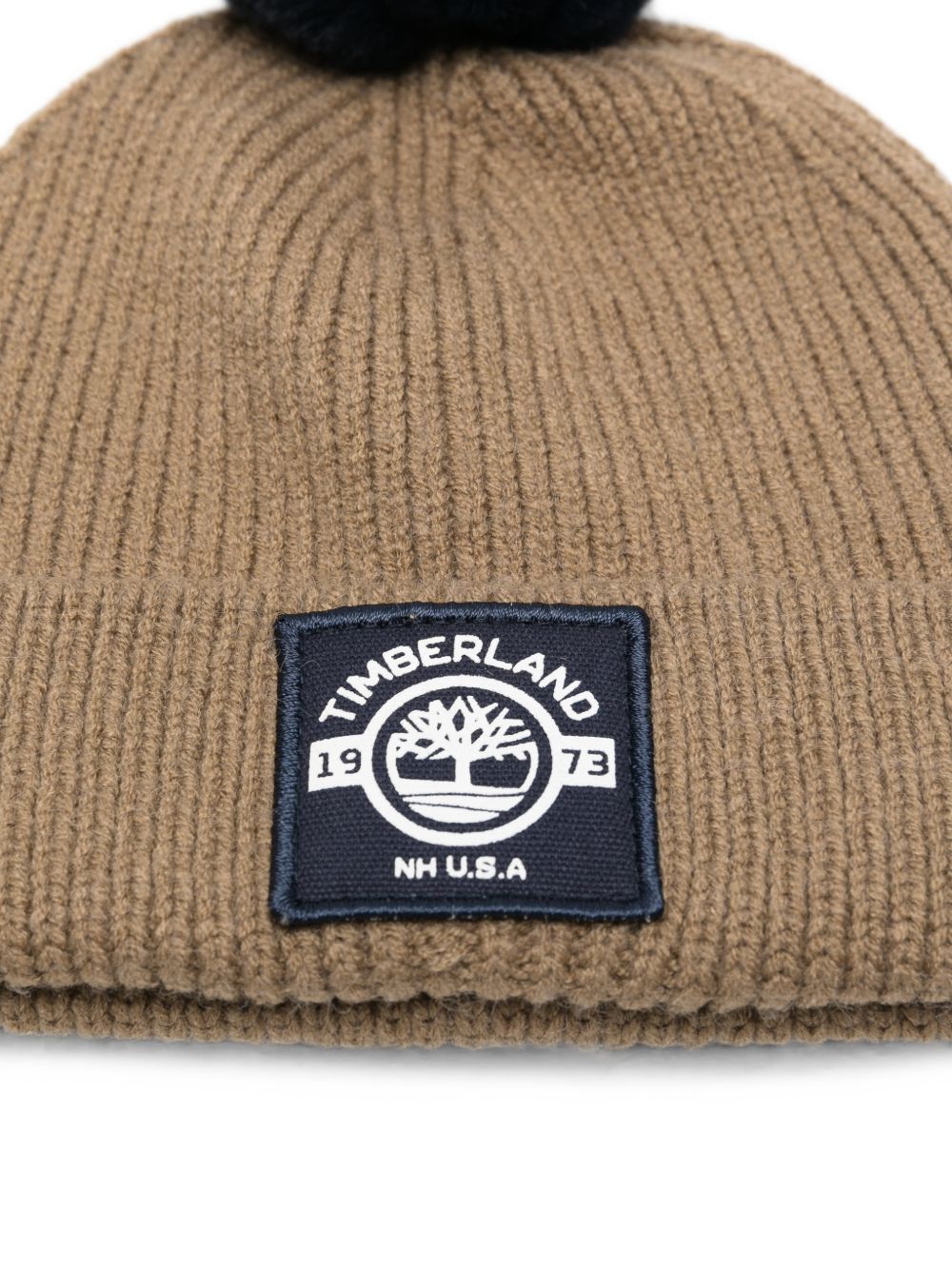 Cappello marrone con pompon blu e patch logo Timberland